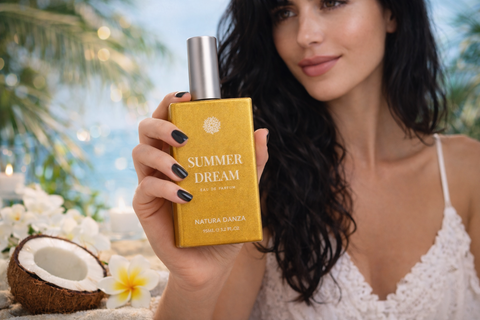 Γυναίκα κρατά το άρωμα Summer Dream της NATURA DANZA σε καλοκαιρινή ατμόσφαιρα με καρύδα και λουλούδια.