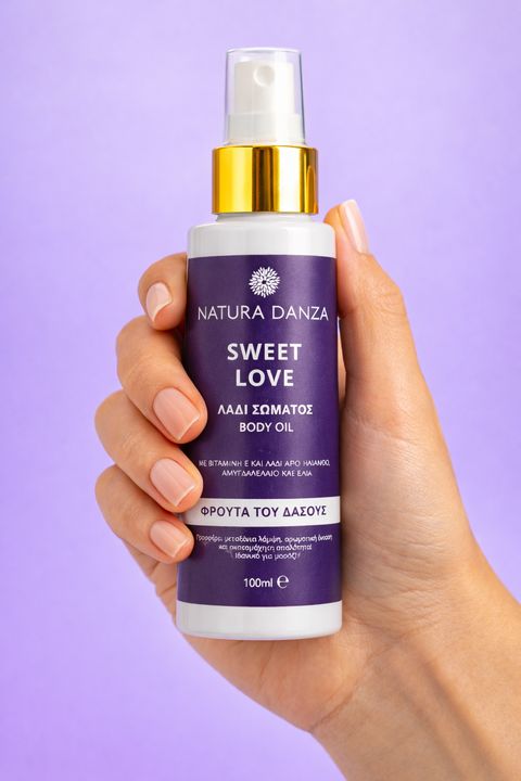 Λάδι σώματος Natura Danza Sweet Love 100ml κρατημένο σε γυναικείο χέρι, με άρωμα φρούτων του δάσους για ενυδάτωση και λάμψη της επιδερμίδας.